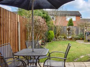 a table and chairs with an umbrella in a backyard at Maureg Formby in Formby