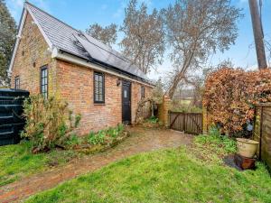 a brick house with a black door in a yard at Wisteria Cottage in Horam