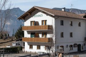 a white building with a balcony on top of it at Grünwald in Salorno