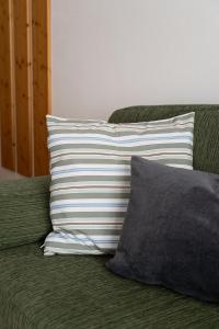 Un sofá verde con dos almohadas. en Grünwald en Salorno
