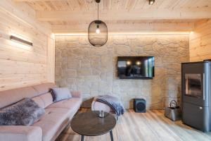 - un salon avec un canapé et une télévision sur un mur en pierre dans l'établissement Bergwaldchalet Tierfreund, à Schierke