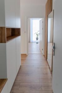 a kitchen with white cabinets and a wooden floor at Avocado apartment Victory port in Liptovský Mikuláš