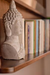 una statua seduta su uno scaffale vicino ai libri di Sale Hotel a Posada