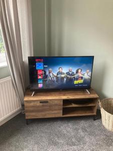 a flat screen tv sitting on top of a wooden entertainment center at Modern cosy home sleeps 6 with parking nr Preston in Leyland