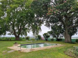 einen Pool inmitten eines Gartens mit Bäumen in der Unterkunft Clivedon Cottage in Sunland
