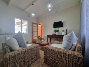 桑蘭德的住宿－Clivedon Cottage，客厅配有2把藤椅和电视