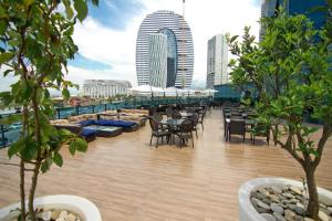 a rooftop deck with tables and chairs and buildings at Sky Tower Hotel in Batumi
