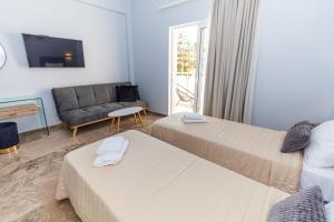 una camera d'albergo con due letti e un divano di Queen Mary Beachfront Studios a Chania