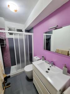 baño con paredes de color púrpura, aseo y lavamanos en El Piso de María, en Vigo