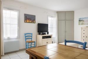 een woonkamer met een tafel en een tv bij Studio "Orneau" proche du port de ST MARTIN in Saint-Martin-de-Ré