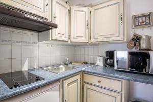 een keuken met witte kasten, een spoelbak en een magnetron bij Studio "Orneau" proche du port de ST MARTIN in Saint-Martin-de-Ré