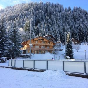 a large wooden building in the snow with trees at Chalet Tho'max in Châtel