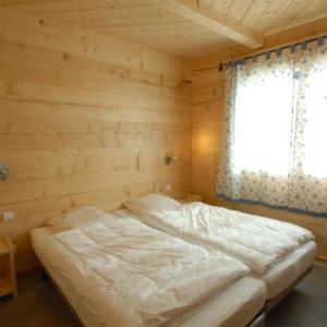 Cama en habitación de madera con ventana en Chalet Tho'max, en Châtel