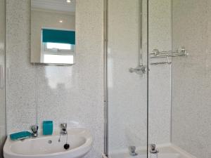 a bathroom with a sink and a glass shower at Puffins in Port Isaac