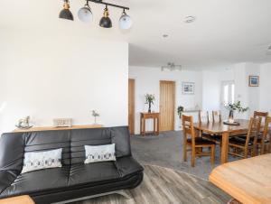 a living room with a black leather couch and a table at Tinkers Patch in Benllech