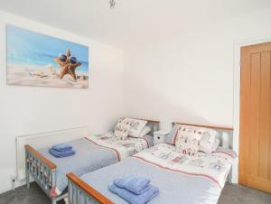 a bedroom with two twin beds and a picture on the wall at Tinkers Patch in Benllech