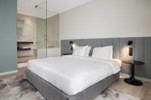 a bedroom with a large white bed and a glass wall at Radisson Blu Hotel, Hasselt in Hasselt