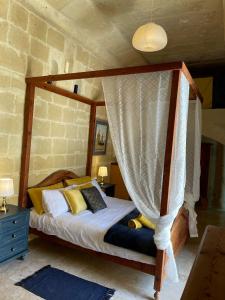 a bedroom with a canopy bed with yellow pillows at Haven Farmhouse B&B in Għarb
