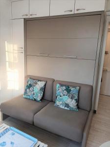 un sofá con 2 almohadas en una habitación en LE PETIT CABOURG de LA COUR NORMANDE Studio coeur de ville -1 à 2 personness, en Cabourg