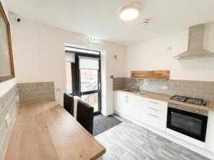 a kitchen with white cabinets and a wooden table at 53 Church Street in Warrington