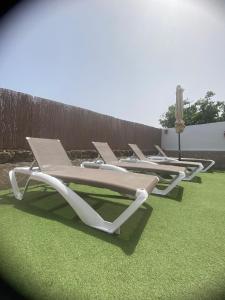 una fila di sedie a sdraio sedute sull'erba di CASA ORILLA! Beautiful private holiday villa with hot tub a La Oliva