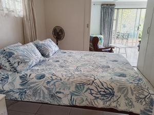 1 dormitorio con 1 cama con manta azul y blanca en Whispering Waves, en Bazley Beach
