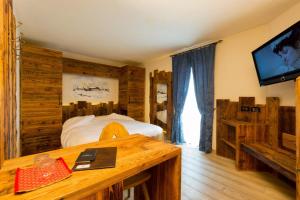 a bedroom with a bed and a tv and a desk at Hotel Pontiglia in Livigno