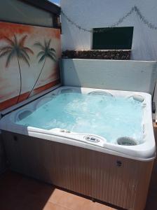 a hot tub in a room with a palm tree painting at CASA ORILLA! Beautiful private holiday villa with hot tub in La Oliva