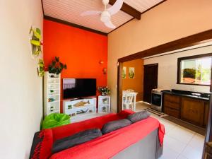 a living room with orange walls and a red couch at Casa no Centro da Ilhabela - Vila - SP in Ilhabela