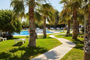 a park with palm trees and a swimming pool at Kampaoh L'Almadrava - Costa Dorada in Platja de l’Almadrava