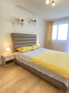 ein Schlafzimmer mit einem Bett mit gelber Bettwäsche und einem Fenster in der Unterkunft Apartman MiNa in Mataruška Banja