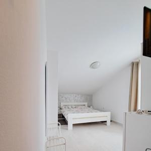 Habitación blanca con cama y nevera. en Sobe ROOMS TEA, en Buje