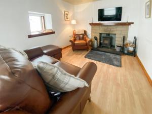 a living room with a couch and a fireplace at Riverside Cottage in Drumnadrochit