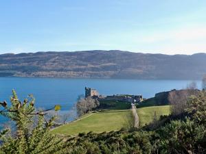 a castle on a hill next to a body of water at Riverside Cottage in Drumnadrochit