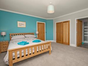 a bedroom with a large bed with blue walls at Quarter Acre House in Challoch