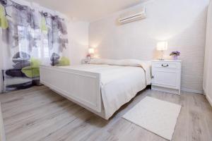 a white bedroom with a large bed and a window at Apartment Brilliant in Dubrovnik