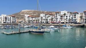 een groep boten aangemeerd in een haven met gebouwen bij Apartement Marina Zina, Agadir in Agadir