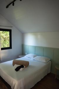 1 dormitorio con 1 cama blanca grande y ventana en Cabanas Serra Grande - Boa Vista, en Gramado