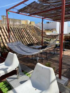 eine Hängematte und Stühle unter einem Baldachin auf einer Terrasse in der Unterkunft Faroway Hostel in Faro