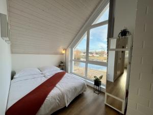 a bedroom with a bed and a large window at Das Vechtehaus n - Nordhorn in Nordhorn