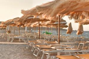 Sale Hotel في بوسادا: مجموعة من الكراسي والمظلات على الشاطئ