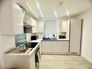 eine weiße Küche mit weißen Schränken und Geräten in der Unterkunft Hemel Apartments - Sea Breeze in Hemel Hempstead