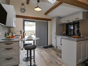 a kitchen with white cabinets and a counter with a table at Bess Cottage in Hebden Bridge