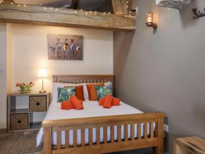 a bedroom with a wooden bed with orange pillows at Bess Cottage in Hebden Bridge