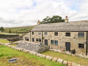 an old stone house in a field with a yard at Bess Cottage in Hebden Bridge