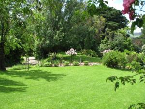 a yard with a green lawn with flowers and trees at Leafield Cottages in Dixons Creek