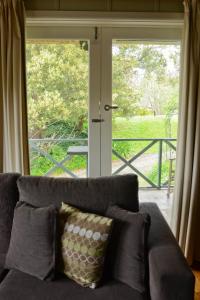 a couch sitting in front of a sliding glass door at Leafield Cottages in Dixons Creek