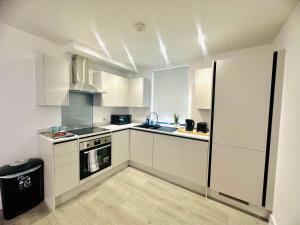 赫默爾亨普斯特德的住宿－Hemel Apartments - Sea Breeze，厨房配有白色橱柜和炉灶烤箱。