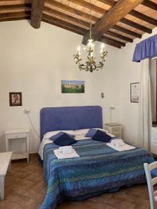 a bedroom with a blue bed and a chandelier at Villa Vacasio Bio-Eco in Pitigliano