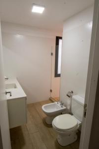 La salle de bains blanche est pourvue de toilettes et d'un lavabo. dans l'établissement Babel Alto, à Buenos Aires